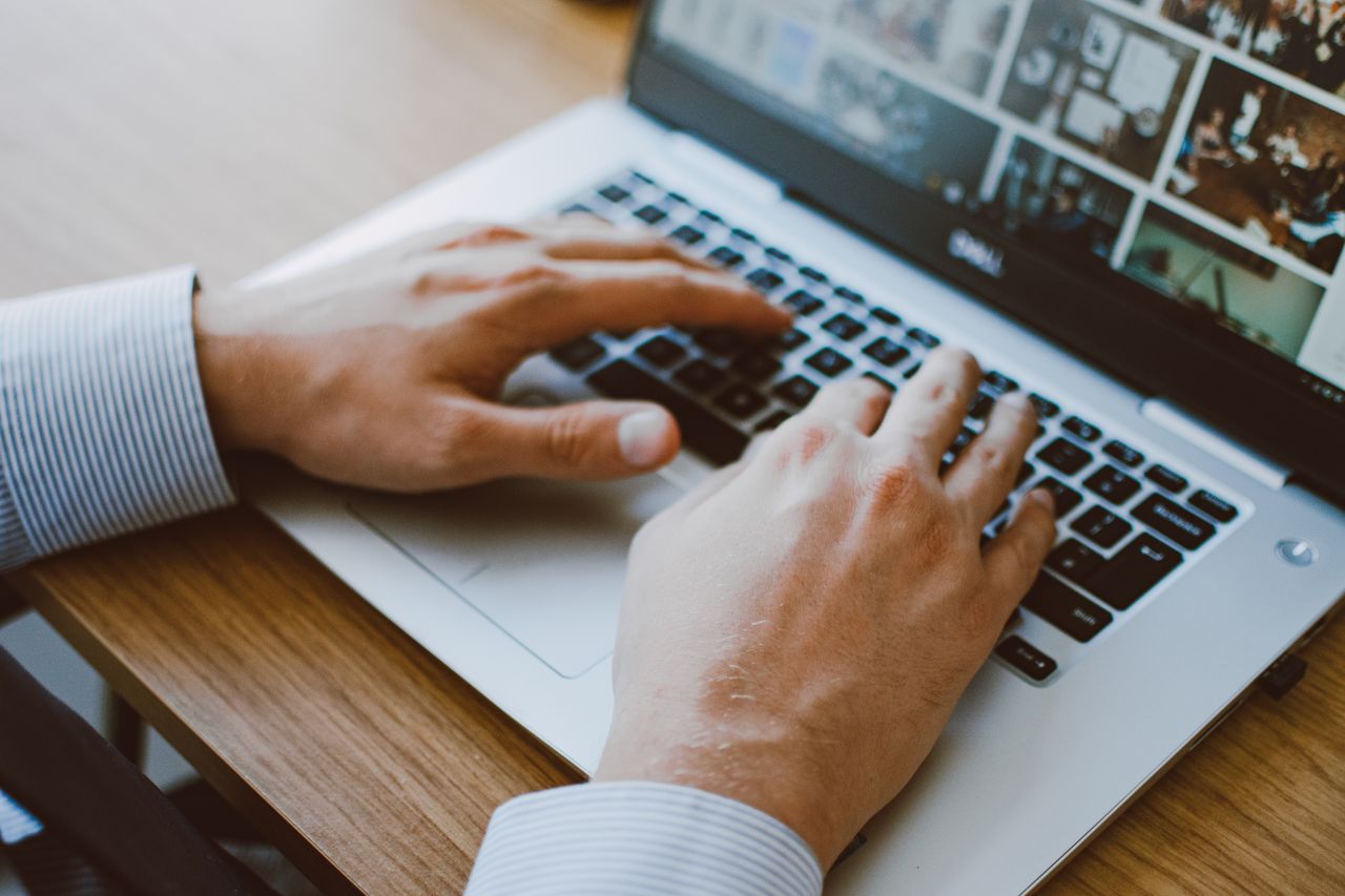 Close-up of a man's hands typing on a laptop keyboard, ideal for illustrating remote work or digital communication.